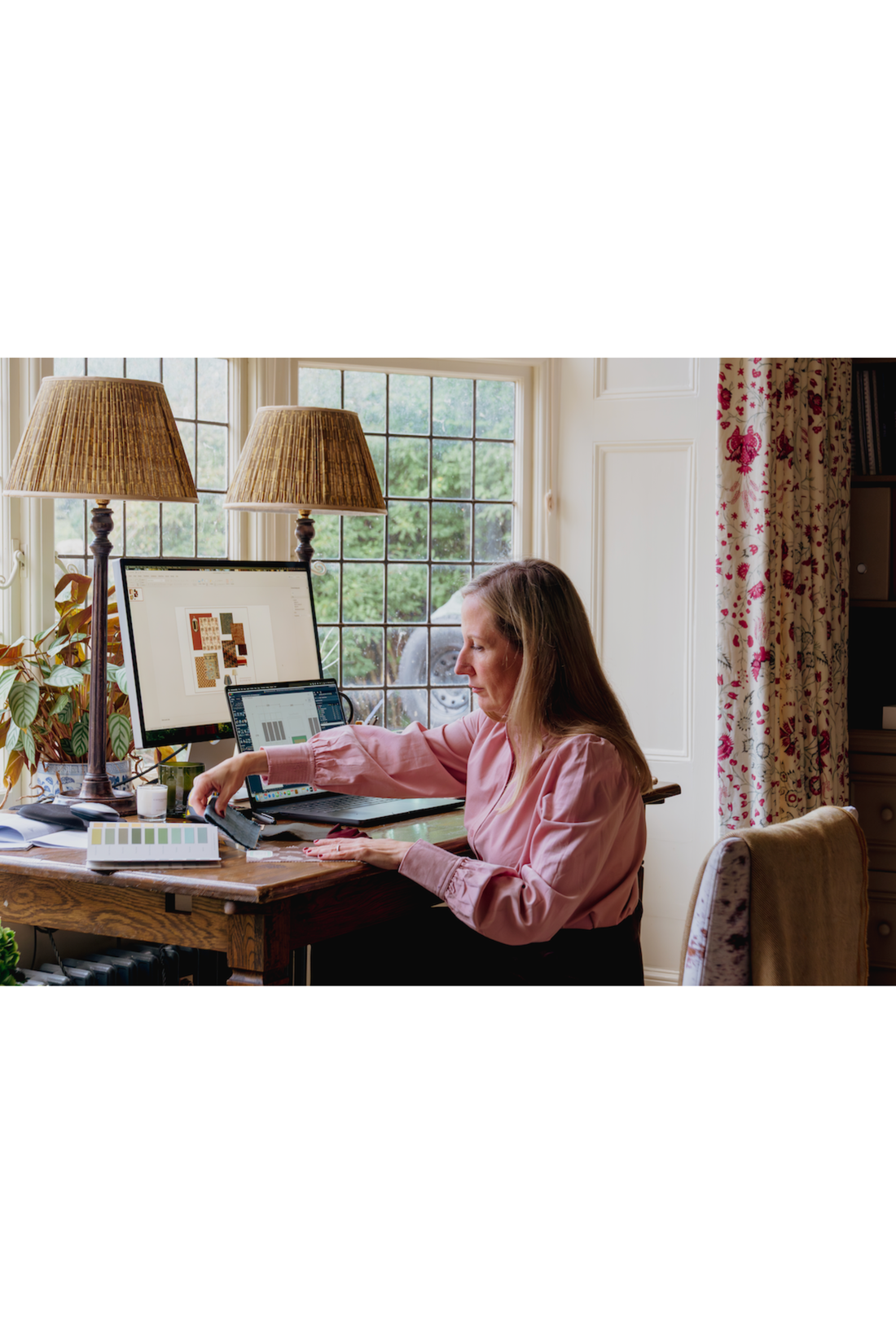 Sam Goold of Danebury Interior Design sitting in her Hamsphire Based Interior Design Studio curating colours and fabrics for Country House interior Design Projects